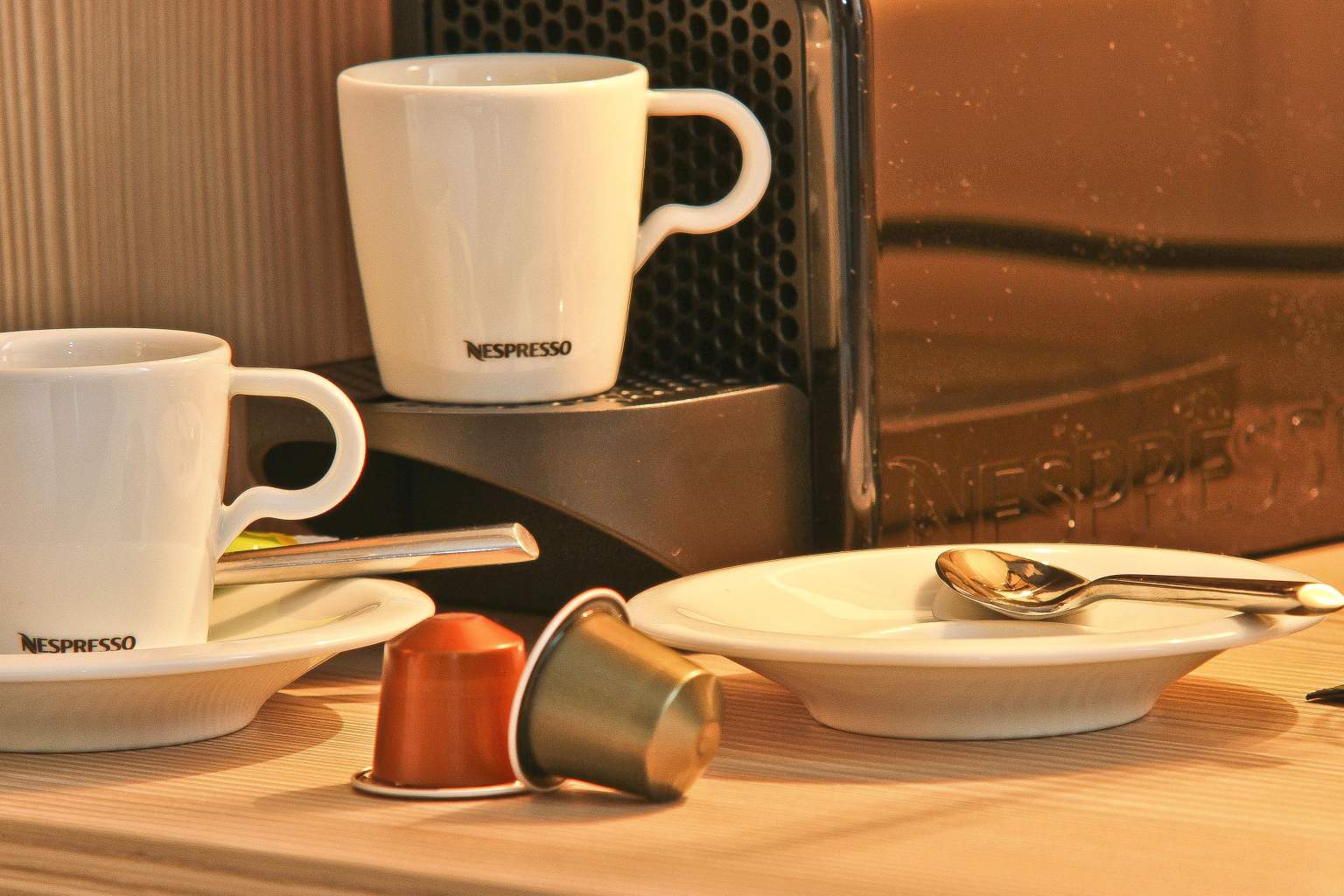 Nespresso coffee machine with cups and coffee capsules.